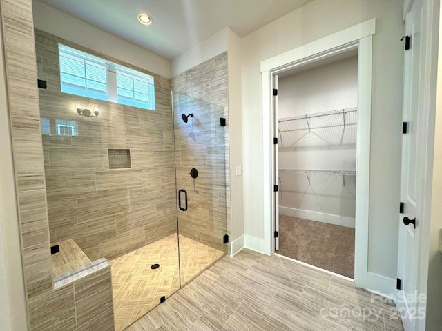 bathroom featuring recessed lighting, baseboards, a spacious closet, and a stall shower