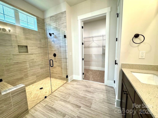 full bath featuring vanity, a walk in closet, and a shower stall