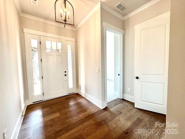 foyer entrance featuring ornamental molding, a notable chandelier, visible vents, and dark wood-type flooring