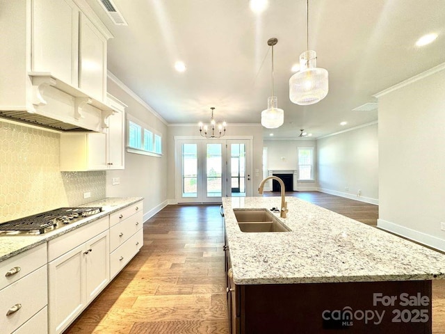 kitchen featuring stainless steel gas cooktop, baseboards, ornamental molding, and a sink