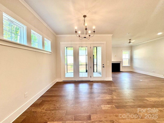 interior space featuring crown molding, baseboards, ceiling fan with notable chandelier, and dark wood finished floors