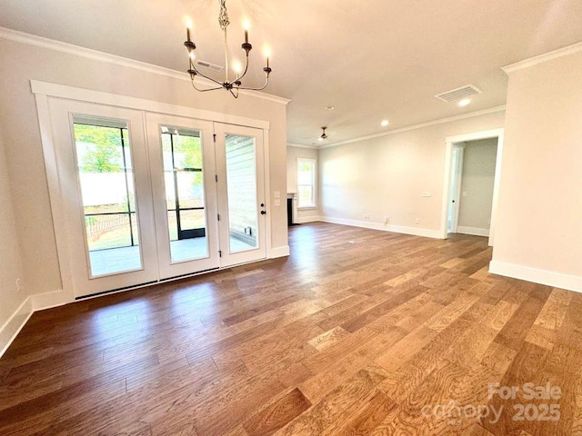 interior space with an inviting chandelier, ornamental molding, wood finished floors, and a wealth of natural light