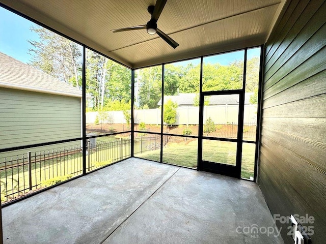 unfurnished sunroom featuring a ceiling fan and a wealth of natural light