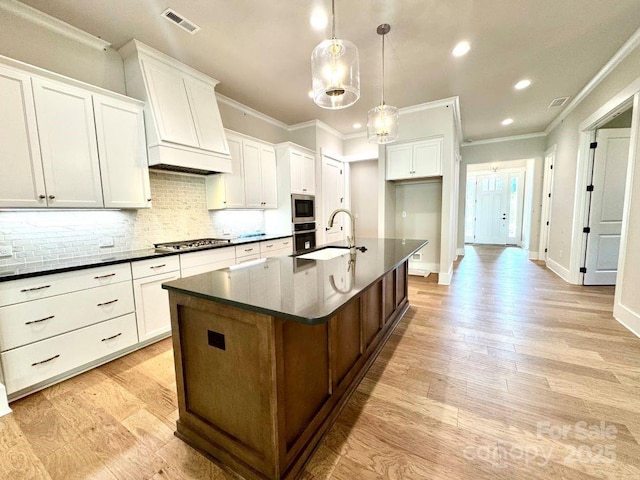 kitchen featuring visible vents, a sink, dark countertops, and ornamental molding