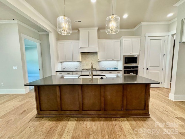 kitchen with a sink, dark countertops, white cabinets, and decorative backsplash