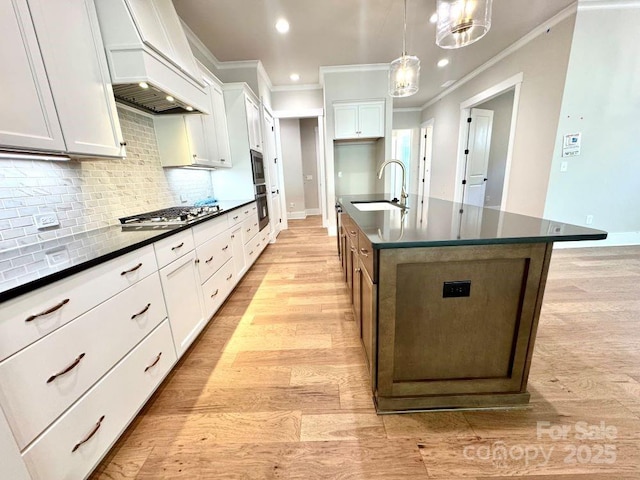 kitchen with oven, dark countertops, a sink, ornamental molding, and custom exhaust hood