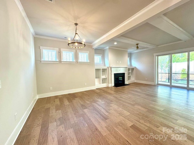 unfurnished living room with beam ceiling, a chandelier, baseboards, wood finished floors, and ornamental molding