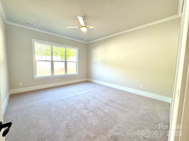 carpeted empty room featuring crown molding, ceiling fan, visible vents, and baseboards