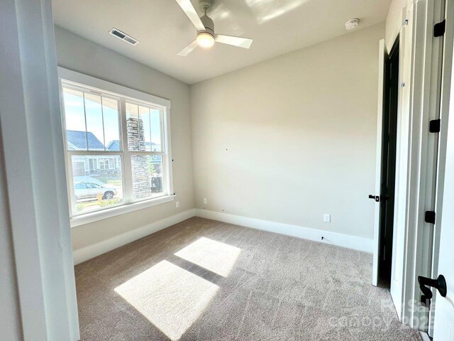 spare room with carpet flooring, a ceiling fan, baseboards, and visible vents