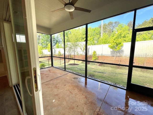 unfurnished sunroom featuring a ceiling fan and a wealth of natural light