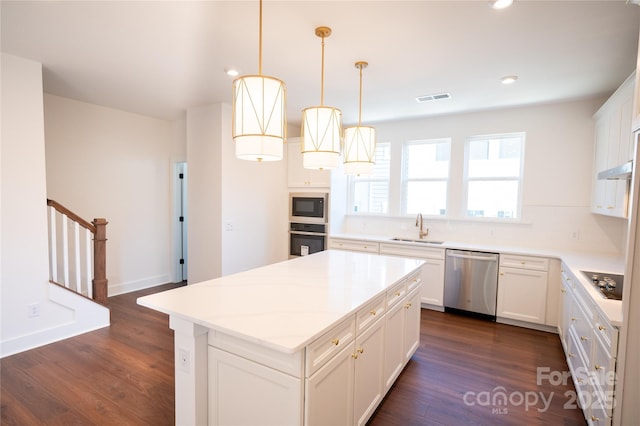 kitchen featuring a sink, a kitchen island, appliances with stainless steel finishes, dark wood-style floors, and visible vents