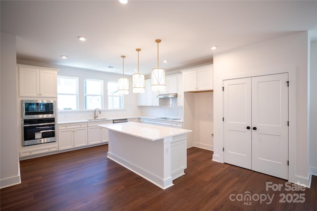 kitchen with dark wood-style floors, white cabinetry, a sink, and appliances with stainless steel finishes