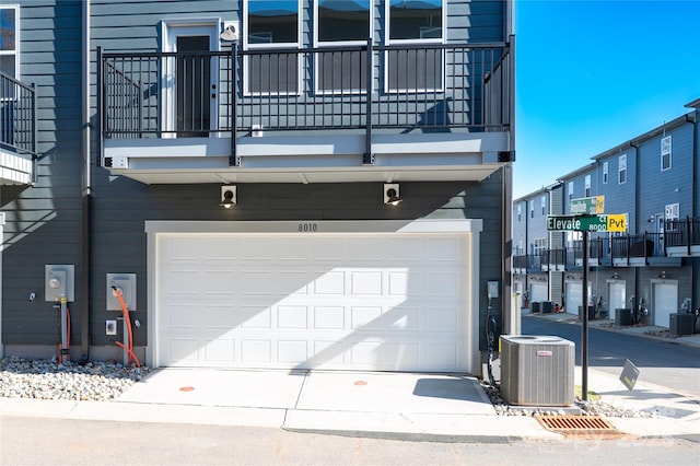 garage with concrete driveway and central air condition unit