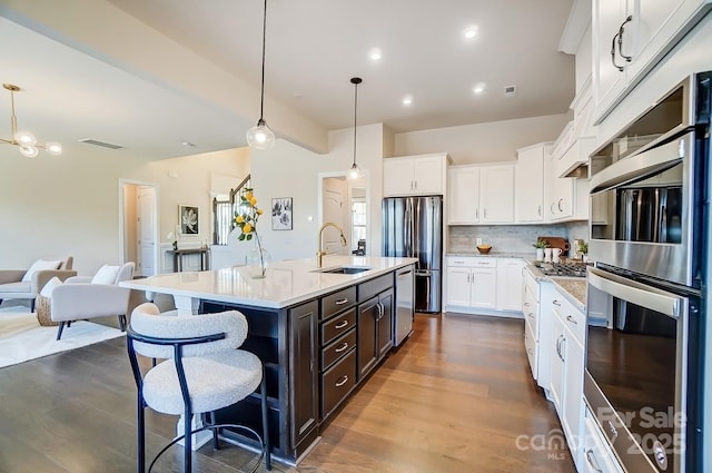 11144 Limehurst Pl, Charlotte, NC 28278 - kitchen featuring appliances with stainless steel finishes, light countertops, white cabinetry, a kitchen island with sink, and dark brown cabinetry