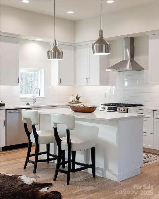 15 Macallan Ln Unit 21, Asheville, NC 28805 - kitchen featuring a sink, a kitchen island, stainless steel dishwasher, light wood-style flooring, and wall chimney range hood