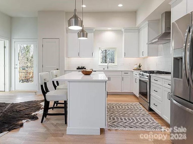 15 Macallan Ln Unit 21, Asheville, NC 28805 - kitchen with light countertops, wall chimney exhaust hood, a kitchen island, appliances with stainless steel finishes, and white cabinetry