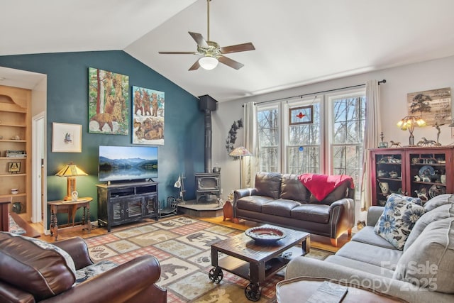 living area with a ceiling fan, vaulted ceiling, and a wood stove