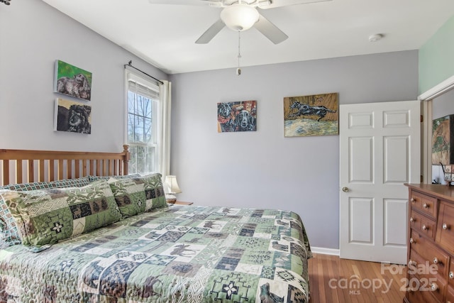 bedroom featuring a ceiling fan, baseboards, and wood finished floors
