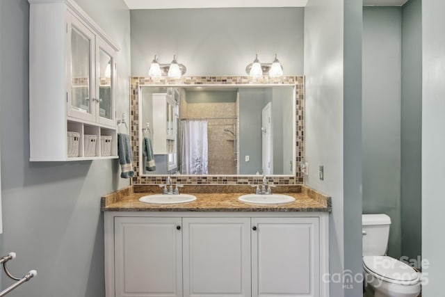 bathroom with backsplash, toilet, a sink, and double vanity
