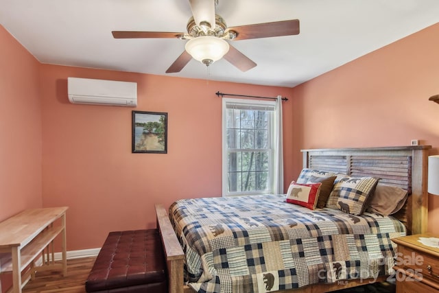 bedroom with baseboards, a wall mounted AC, wood finished floors, and a ceiling fan