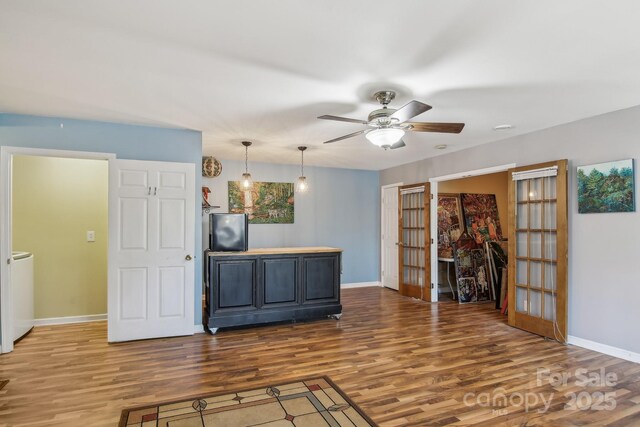 interior space featuring baseboards, ceiling fan, wood finished floors, and french doors