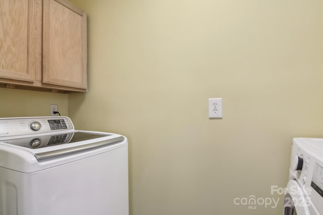 laundry room featuring independent washer and dryer and cabinet space