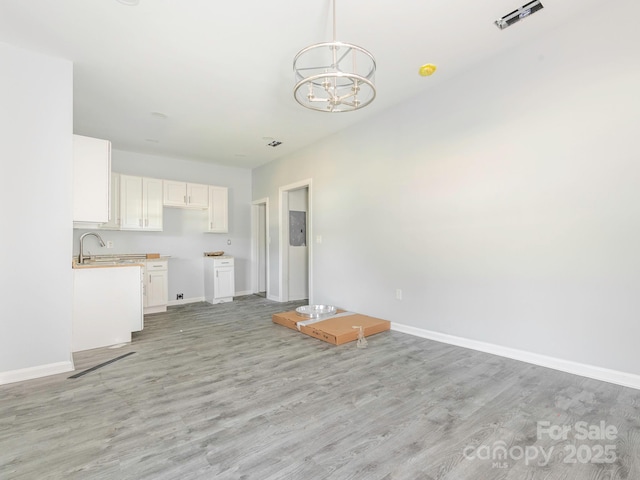 108 Graham St, Chester, SC 29706 - unfurnished living room featuring an inviting chandelier, light wood-type flooring, baseboards, and a sink