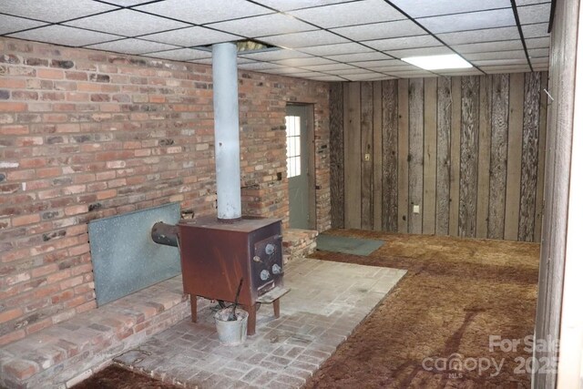 2610 Indian Grave Rd, Lenoir, NC 28645 - below grade area featuring a wood stove, wooden walls, and a paneled ceiling