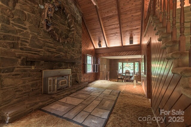 2610 Indian Grave Rd, Lenoir, NC 28645 - unfurnished living room with high vaulted ceiling, wood ceiling with exposed beams, wood walls, and carpet floors