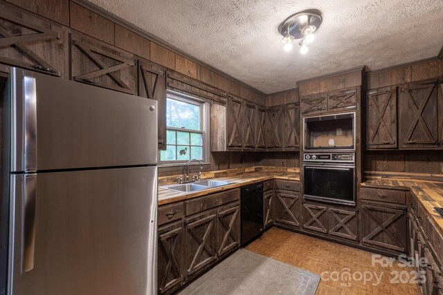 2610 Indian Grave Rd, Lenoir, NC 28645 - kitchen with black appliances, a sink, a textured ceiling, wooden walls, and dark brown cabinets
