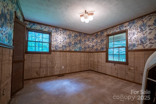2610 Indian Grave Rd, Lenoir, NC 28645 - empty room featuring healthy amount of natural light, wainscoting, wallpapered walls, a textured ceiling, and ornamental molding