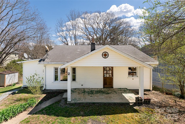 bungalow with a patio, a chimney, and roof with shingles