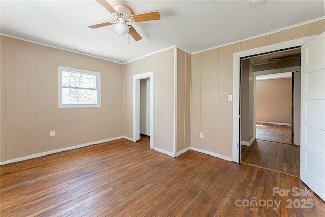 unfurnished bedroom with wood-type flooring, a ceiling fan, crown molding, and baseboards
