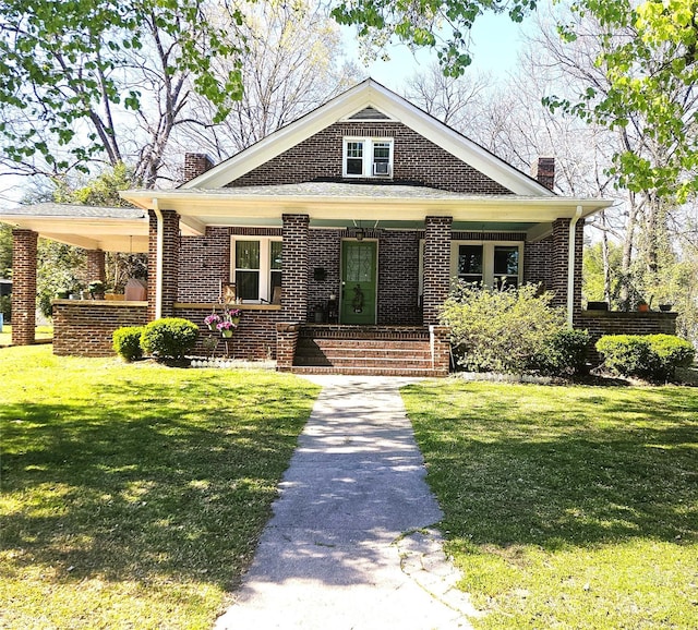 view of front of house with a chimney, a front lawn, a porch, and brick siding