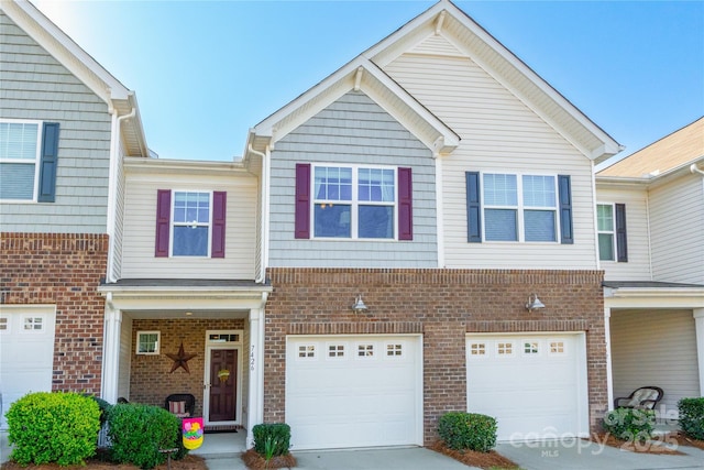 townhome / multi-family property with driveway, a garage, and brick siding