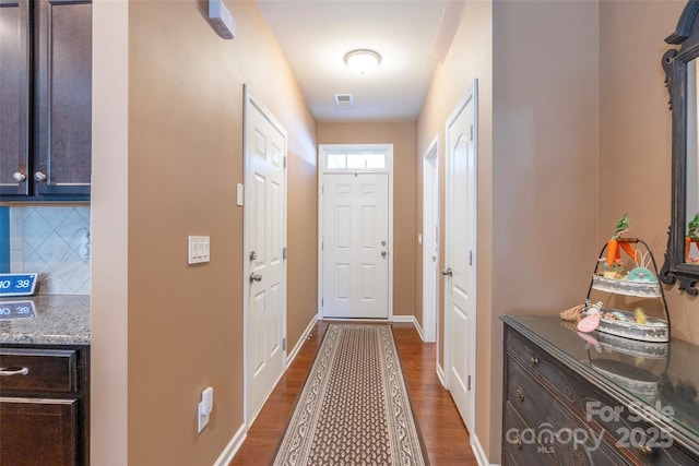 doorway featuring dark wood-style floors, baseboards, and visible vents