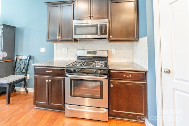 kitchen with light stone countertops, stainless steel appliances, light wood-style floors, and tasteful backsplash