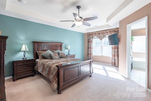 bedroom with baseboards, a raised ceiling, ceiling fan, visible vents, and light carpet