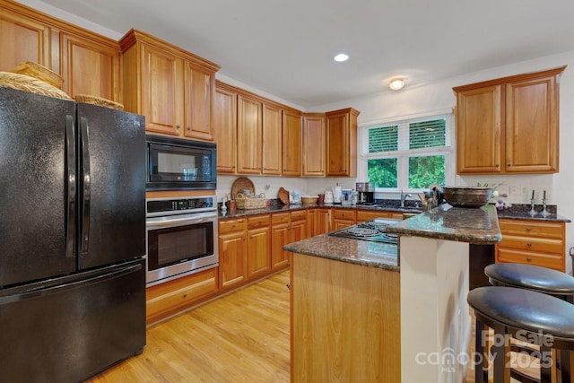 1102 High Brook Dr, Waxhaw, NC 28173 - kitchen with black appliances, a breakfast bar area, light wood-style floors, dark stone counters, and a sink