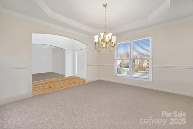 1102 High Brook Dr, Waxhaw, NC 28173 - spare room featuring ornamental molding, a tray ceiling, carpet, a chandelier, and arched walkways