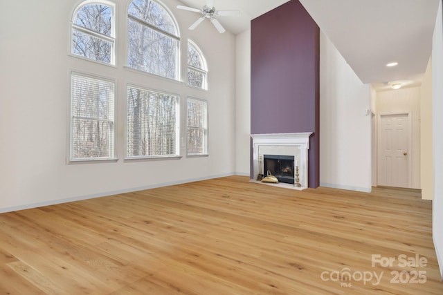 1102 High Brook Dr, Waxhaw, NC 28173 - unfurnished living room featuring light wood finished floors, a high ceiling, ceiling fan, and a fireplace with flush hearth
