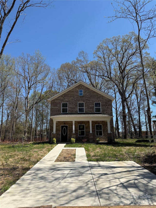 view of front of property with brick siding, a porch, and a front yard