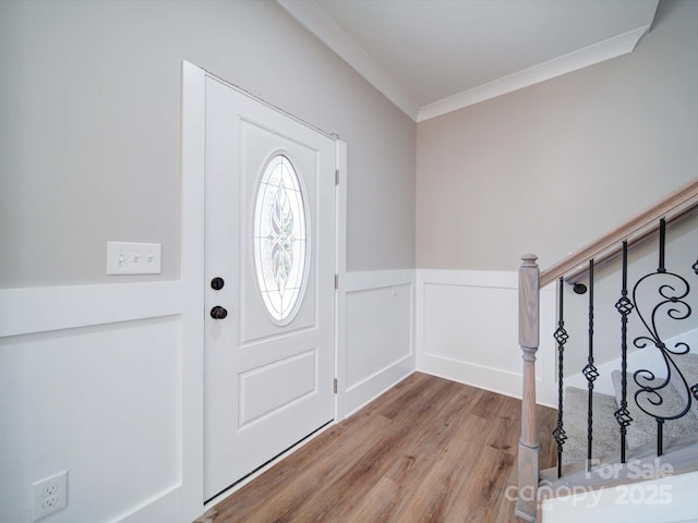 entryway featuring a wainscoted wall, stairs, wood finished floors, a decorative wall, and ornamental molding