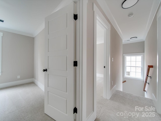 hallway with carpet, an upstairs landing, baseboards, visible vents, and ornamental molding