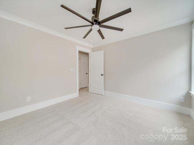 unfurnished room featuring a ceiling fan, ornamental molding, baseboards, and light colored carpet