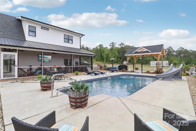 view of pool with a patio area, a fenced in pool, a water slide, a gazebo, and fence