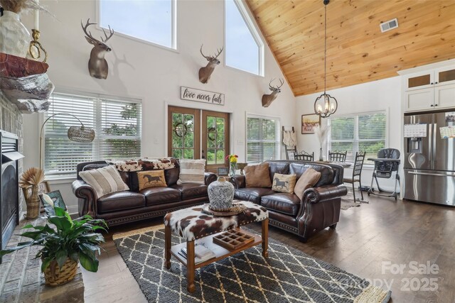 living area with visible vents, a chandelier, a wealth of natural light, dark wood-style flooring, and high vaulted ceiling