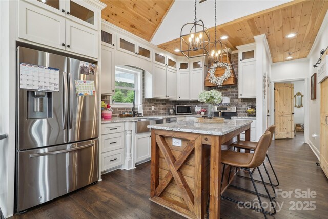 kitchen with wood ceiling, tasteful backsplash, white cabinets, appliances with stainless steel finishes, and dark wood-type flooring