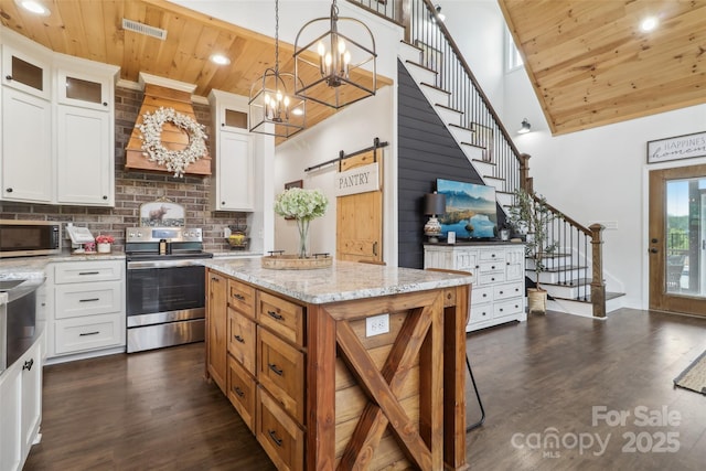 kitchen with dark wood-style floors, wooden ceiling, a barn door, stainless steel appliances, and decorative backsplash