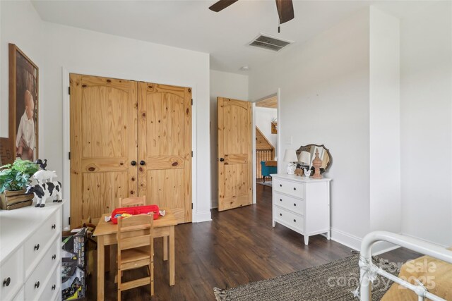 interior space with dark wood-style floors, a ceiling fan, visible vents, and baseboards